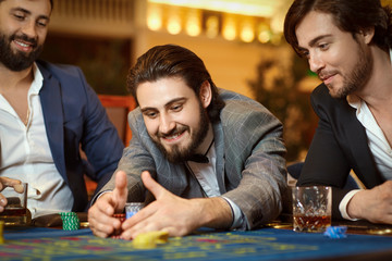 Fototapeta premium Group man gambler in a suit at table roulette playing poker at a casino.