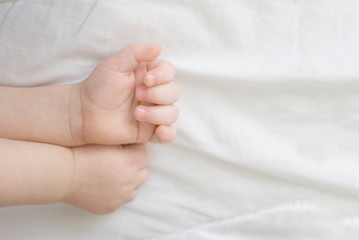 hands of a sleeping baby in the form of a heart on a white background. A child's dream