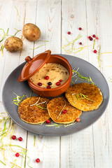 Fototapeta na wymiar potato pancakes and machanka with cranberries on white wooden background in rustic style, example of menu in traditional belarusian restaurant, vertical photo