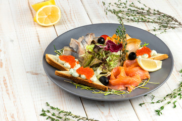 lunch menu of food restaurant on white wooden background in rustic style, appetizer with smoked salmon, butterfish and herring, wheat croutons with cream cheese, mix salad with lemon slices