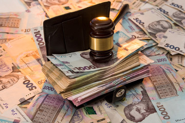 black leather wallet full of Ukrainian hryvnia. 1000 new buyer. The judge's hammer lies on the money.