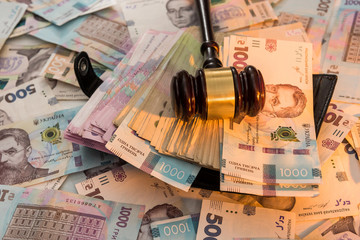 black leather wallet full of Ukrainian hryvnia. 1000 new buyer. The judge's hammer lies on the money.