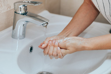 Woman use soap and washing hands under the water tap. Hygiene concept hand detail.