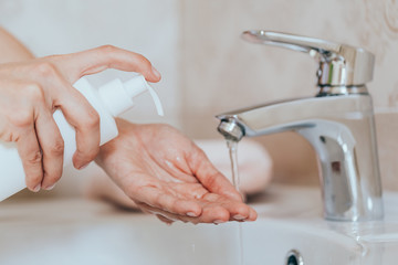 Woman use soap and washing hands under the water tap. Hygiene concept hand detail.