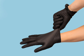man puts on sterile black gloves on a blue background. Hazard, hygiene, control - obrazy, fototapety, plakaty