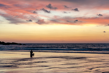 young unrecognizable woman meditating at agonda beach at sunset in goa, india