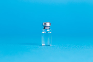 Obraz na płótnie Canvas Closeup vaccine bottle on blue isolated background. No inscription, blank for advertising.