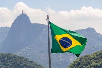 flag of brazil with image of christ the redeemer in the background in rio de janeiro.