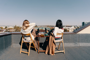 Two attractive girls enjoy a tea party on the rooftop overlooking the city