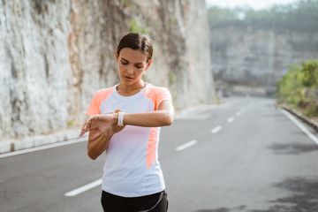 Young athlete workout at park and adjusting smart watch. woman setting smartwatch before jogging