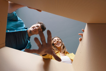 Happy couple opening a cardboard box and looking inside