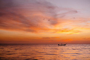 Boat at a beautiful sunset in Phuket, Thailand. Amazing seascape, Indian ocean with boat silhouette on a horizon