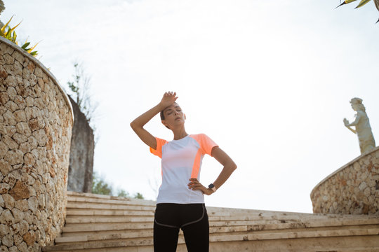 Fitness sport girl resting after intensive run, young attractive runner taking break after jogging outdoors