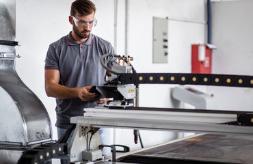 Engineer setup plasma cutter for work in metalwork workshop on tablet.