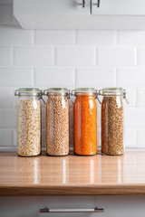 Glass jars with dried legumes and grains on a kitchen counter