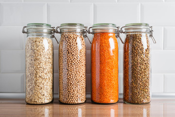 Closeup of glass jars with dried legumes and grains on a kitchen counter