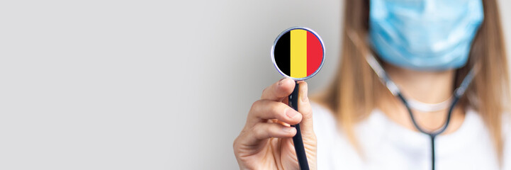 female doctor holding a stethoscope on a light background. Added flag of Belgium. Concept medicine,...