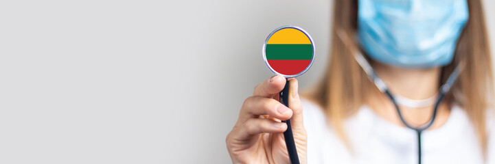 female doctor in a medical mask holds a stethoscope on a light background. Added flag of Lithuania....