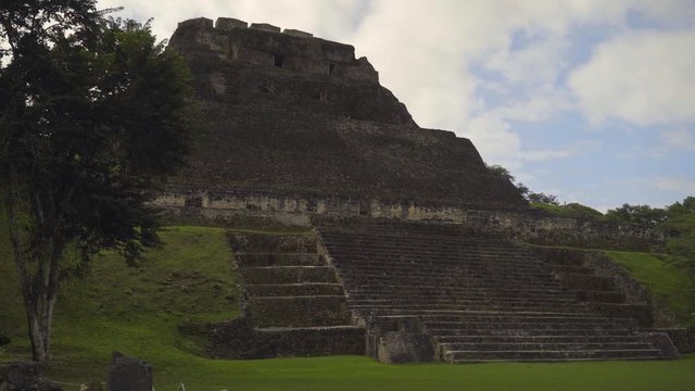 Foreground wipe reveals Xunantunich Mayan ancient site in Belize, pyramid, sky, and clouds all visible in this cinematic introduction shot.