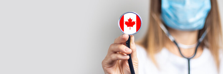 female doctor in a medical mask holds a stethoscope on a light background. Added flag of Canada....