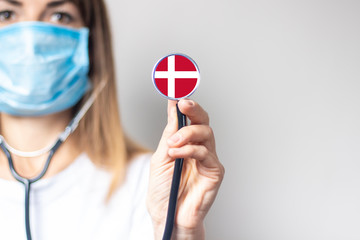 female doctor holding a stethoscope on a light background. Added flag of Denmark. Concept medicine,...