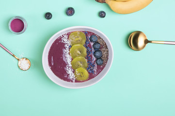 Acai berry smoothie bowl topped with seeds, flowers and blackberries