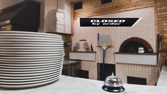 Closed by order sign swinging on empty pizzeria restaurant kitchen, crisis unemployment concept