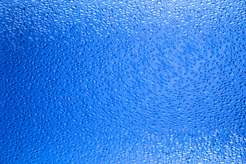 Blue translucent relief glass, gradient background. Water drops on blue background
