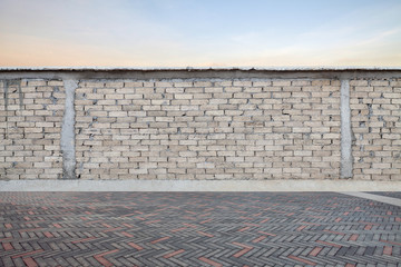 Gray brick wall with empty brick pavement