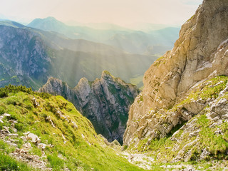 Deep mountain valley with rocks on a foreground in sunlight