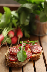 Radish  with bread and sausage on a wooden background. Rustic. Fresh herbs in a bucket. Background image, copy space