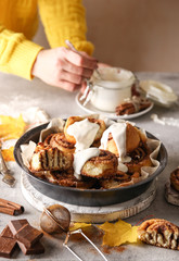 The concept of American cuisine. Pastries and desserts. Cinnabon and white glaze with hands. Buns with cinnamon and cream cheese on a light background. Background image, copy space