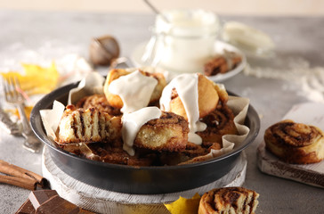 The concept of American cuisine. Pastries and desserts. Cinnabon with cinnamon and white glaze. Buns with cinnamon and cream cheese on a light background. Background image, copy space