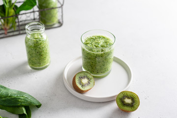 Fresh organic green smoothie with spinach, apple and kiwi in a glass on white background. Detox, dieting, healthy food.