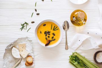 Pumpkin cream soup with cheese and onions on a white board. Still life flat lay