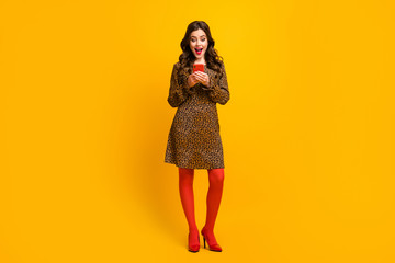Full length body size view of her she nice attractive lovely cheerful cheery amazed wavy-haired girl using digital device app sale isolated over bright vivid shine vibrant yellow color background