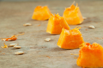 Slices of raw pumpkin ready to use for cooking on a wooden table. Vegetarian cuisine. The basics of a healthy diet.