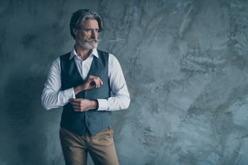 Portrait of stunning old dandy man adjust button sleeves prepare for work job meeting look good copy space wear brown shirt outfit isolated over concrete wall grey color background