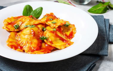 Ravioli with tomato sauce and basil on a concrete background. Delicious pasta