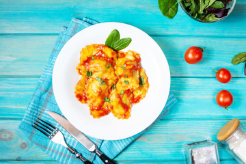 Ravioli with tomato sauce and basil on a blue wooden background. Delicious pasta