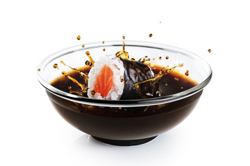 Sushi maki drops in a bowl with soy sauce isolated on white background. Splash of soy sauce.