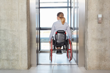 Businesswoman in a wheelchair drives with the elevator