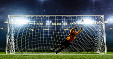 Goalkeeper is trying to save from a goal on an empty soccer stadium. No spectators on the tribunes....