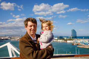 Happy cute little toddler girl on arms of dad on cruise ship. Adorable baby child and father, middle-aged man making family vacations cruising through Europe and Mediterranean Sea