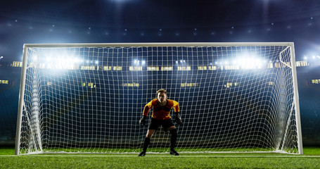Goalkeeper is trying to save from a goal on an empty soccer stadium. No spectators on the tribunes....