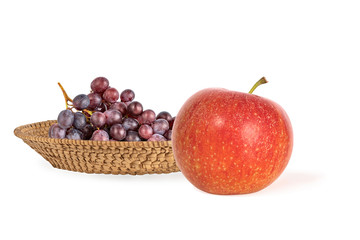 ripe red apple and juicy grapes in a wicker basket. Healthy eating concept