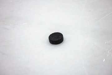 Old black Ice Hockey puck on ice arena hockey rink.