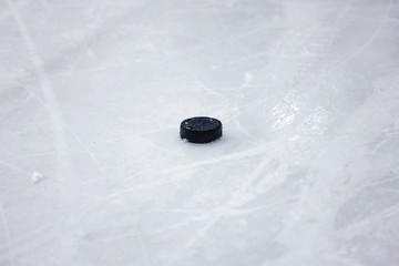 Black, old ice hockey puck on ice rink ice.