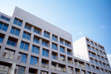 Exterior of new apartment buildings on a blue cloudy sky background. No people. Real estate business concept.