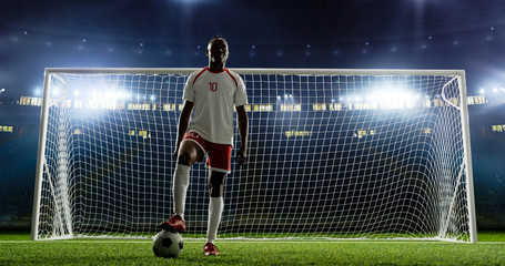 Soccer player is standing in front of the goal on the empty soccer stadium. No spectators on the...